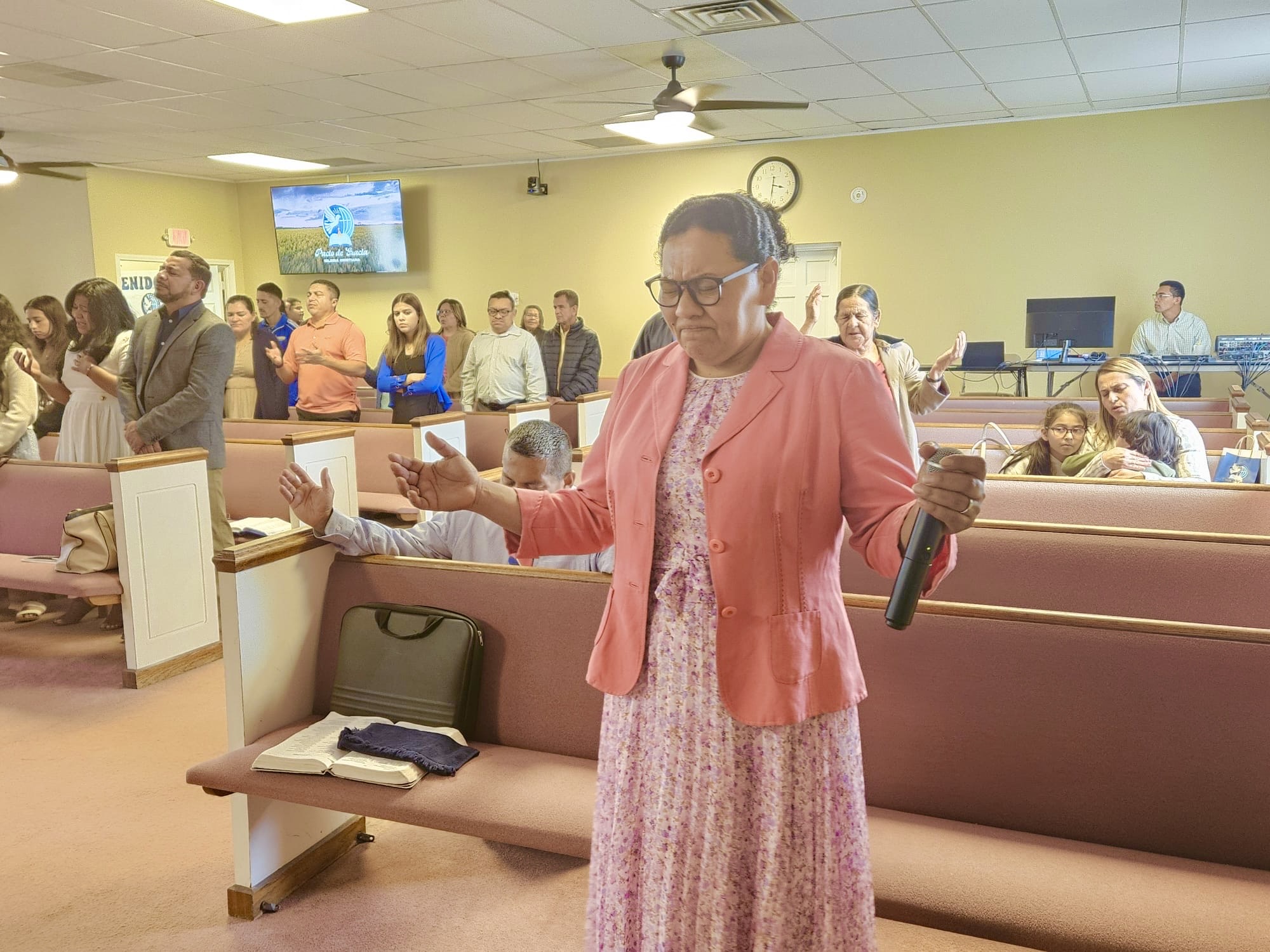  Pastora de la Iglesia Cristiana Pacto de Gracia en Charlotte participando en el culto, con Biblia en mano y congregación reunida en adoración.