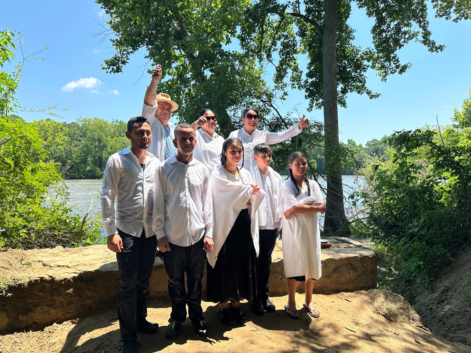 Bautizos de la Iglesia Cristiana Pacto de Gracia en Charlotte, con hermanos y hermanas vestidos de blanco reunidos junto al río en un ambiente natural y festivo.
