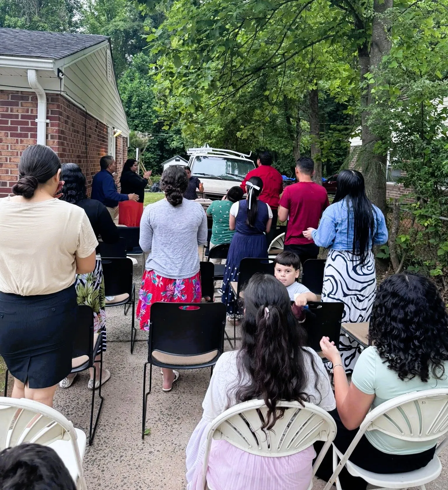 Grupo de crecimiento de la Iglesia Cristiana Pacto de Gracia en Charlotte reunido en un patio al aire libre, con hermanos y hermanas participando en oración, enseñanza y comunión fraternal.