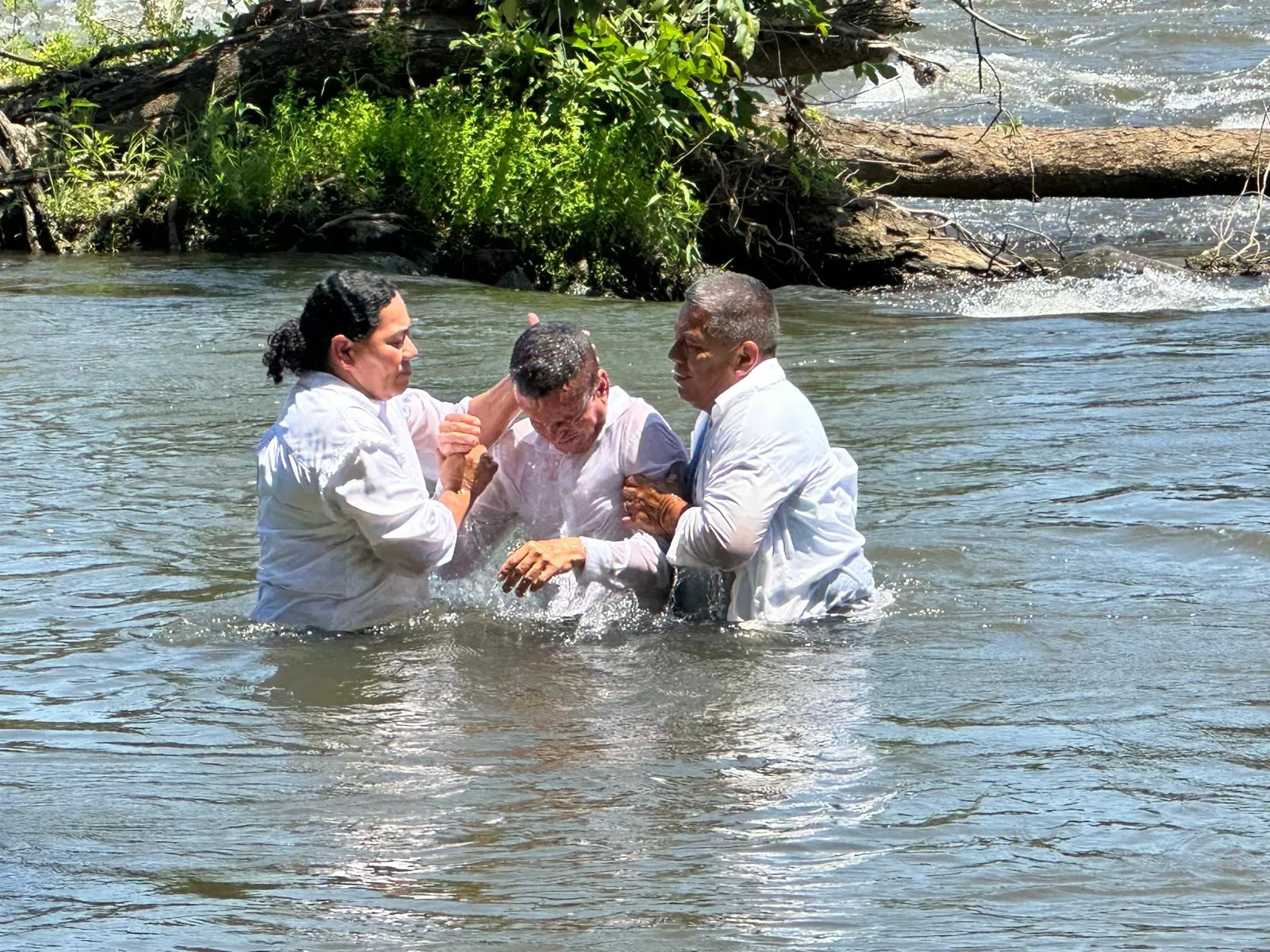 Pastores de la Iglesia Cristiana Pacto de Gracia en Charlotte realizando bautizos en el río, acompañando a los hermanos en el momento de inmersión en agua como símbolo de nueva vida en Cristo.