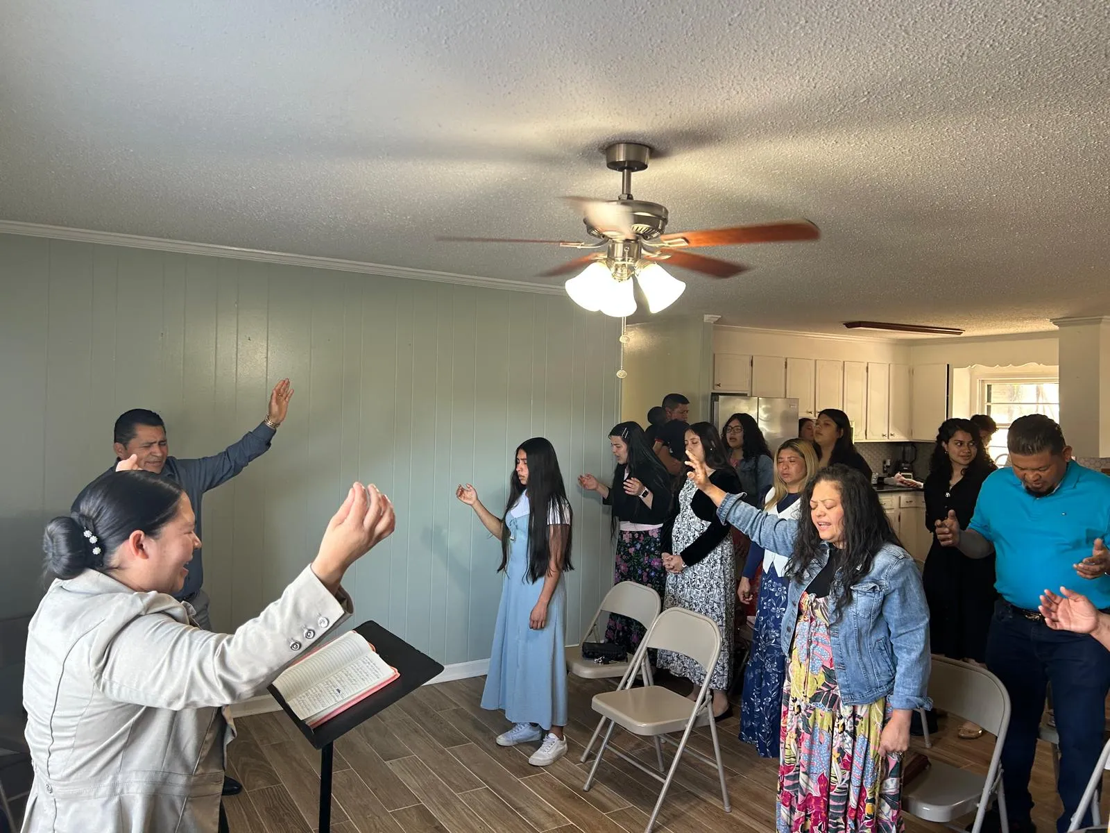 Grupo de crecimiento de la Iglesia Cristiana Pacto de Gracia en Charlotte reunido en un hogar, con hermanos y hermanas participando en oración, alabanza y estudio bíblico.