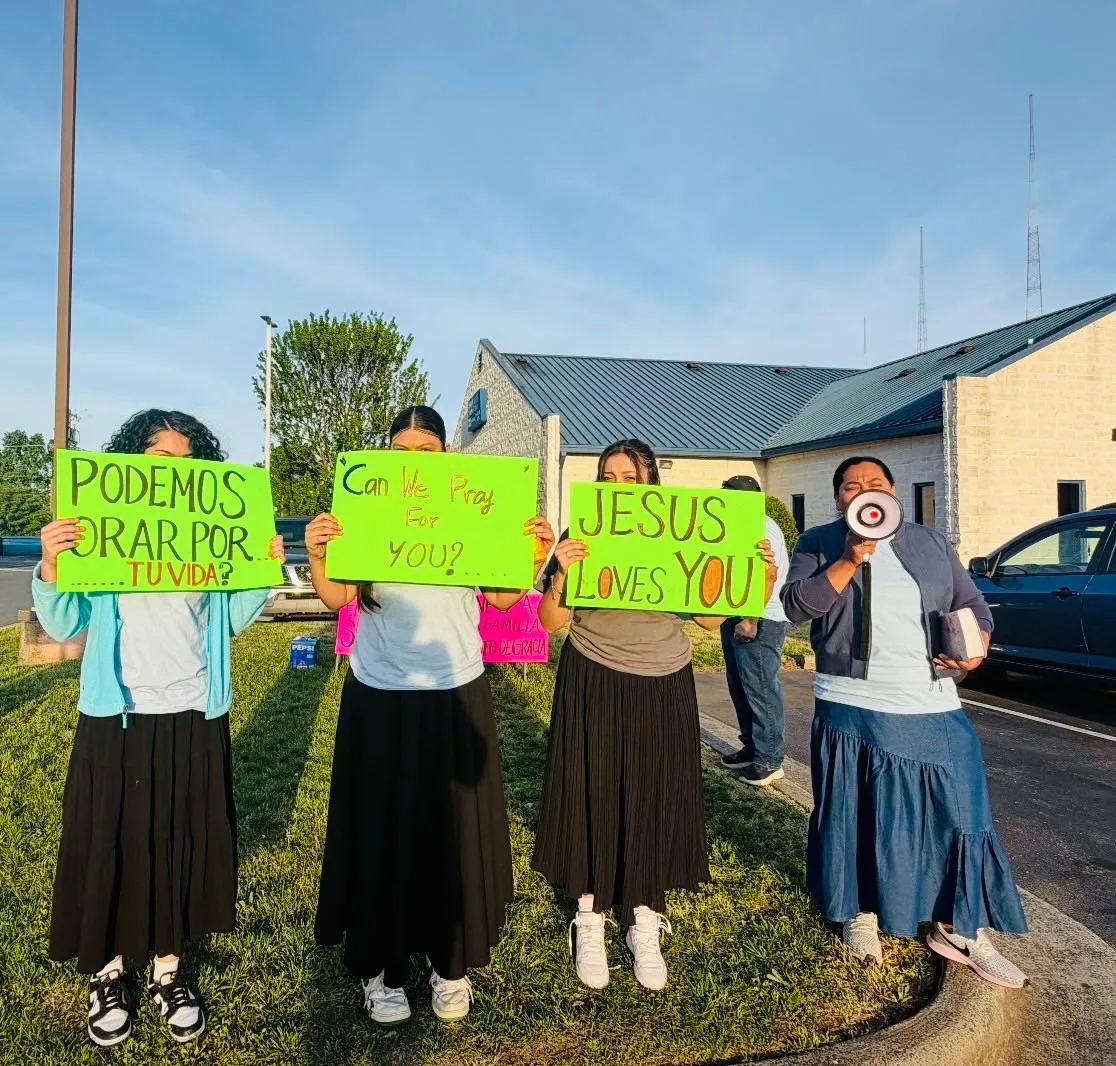 Miembros de la Iglesia Cristiana Pacto de Gracia en Charlotte sirviendo a la comunidad, sosteniendo carteles de ánimo con mensajes como “Good Luck”, “You Got This” y “We Believe In You”.