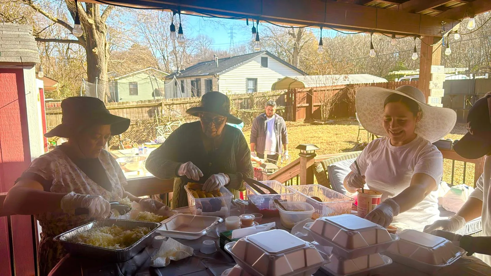 Miembros de la Iglesia Cristiana Pacto de Gracia en Charlotte reunidos en un patio, compartiendo alimentos y bebidas como parte de las actividades misioneras, fortaleciendo la comunión y el servicio comunitario.